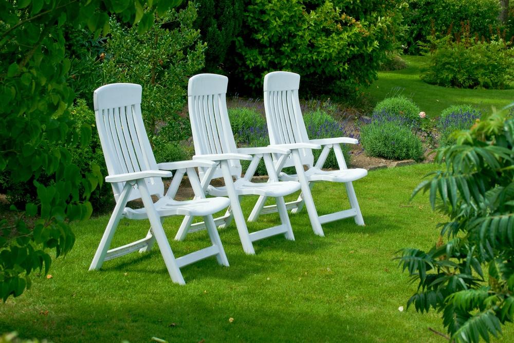 Biele záhradné stoličky na trávniku v parku