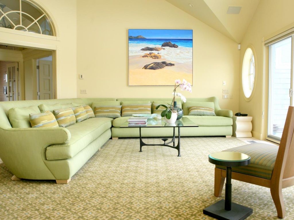 Šviesus gyvenamasis kambarys su šviesiai žalia sofa