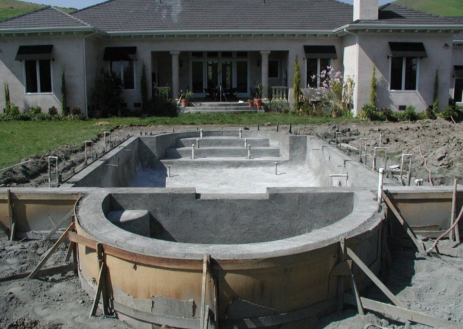 Bouw van een betonnen zwembad in een buitenwijk