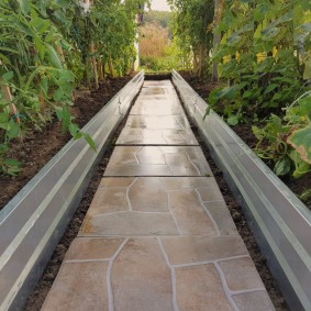 A path made of decorative stone between the beds with cucumbers