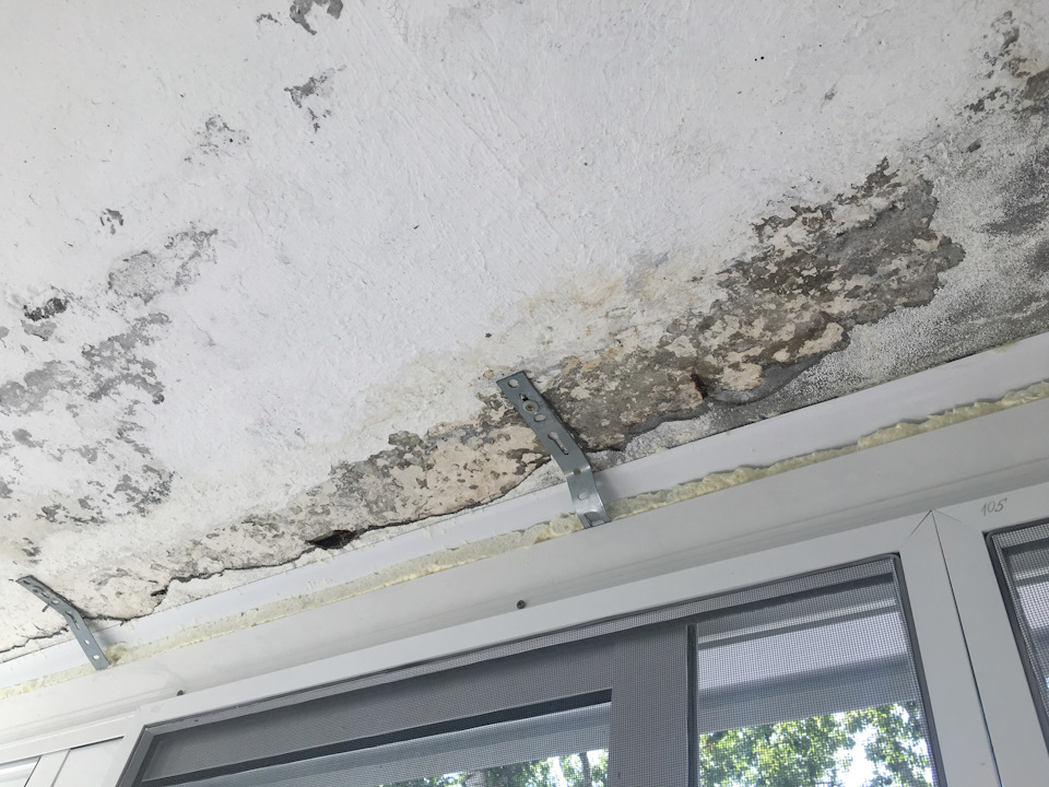 Destroyed plaster on the concrete slab of the ceiling of the balcony